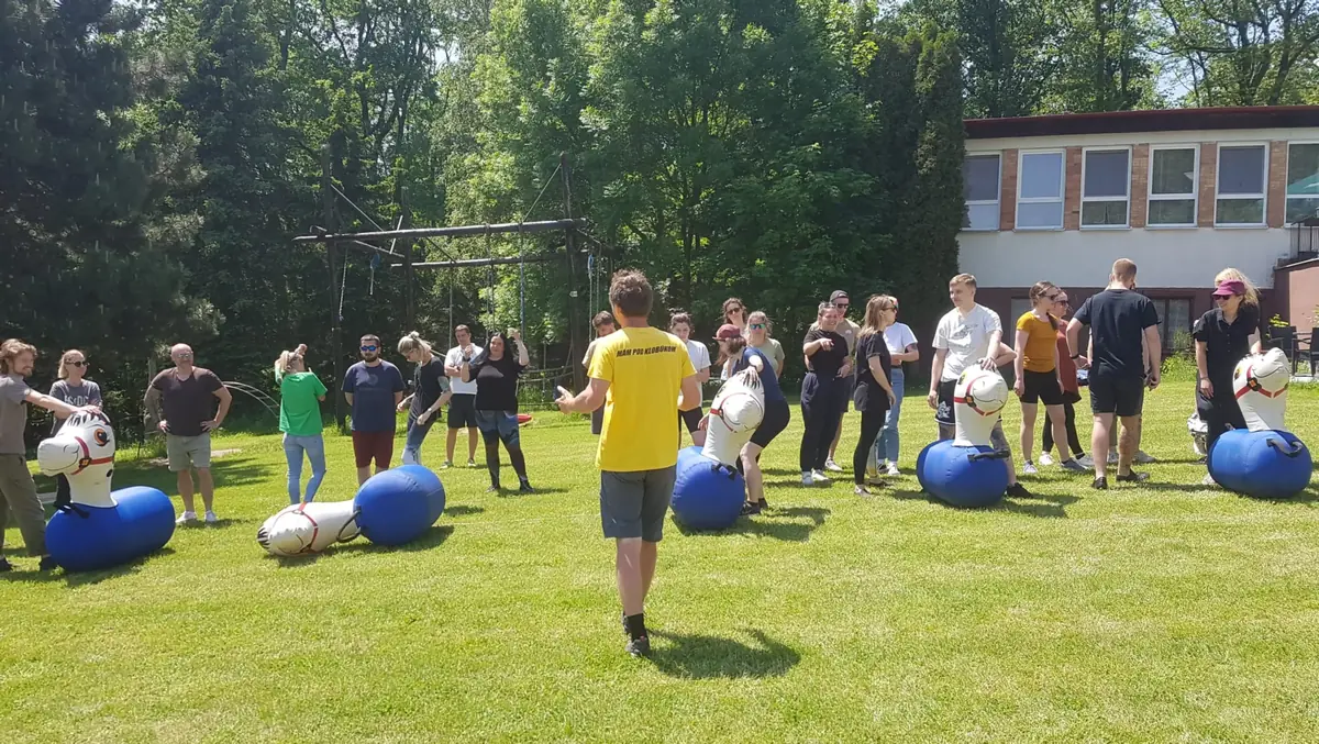 Skupina kolegov sa pripravuje na pohybovú aktivitu počas outdoor firemnej párty hre vonku na trávniku.