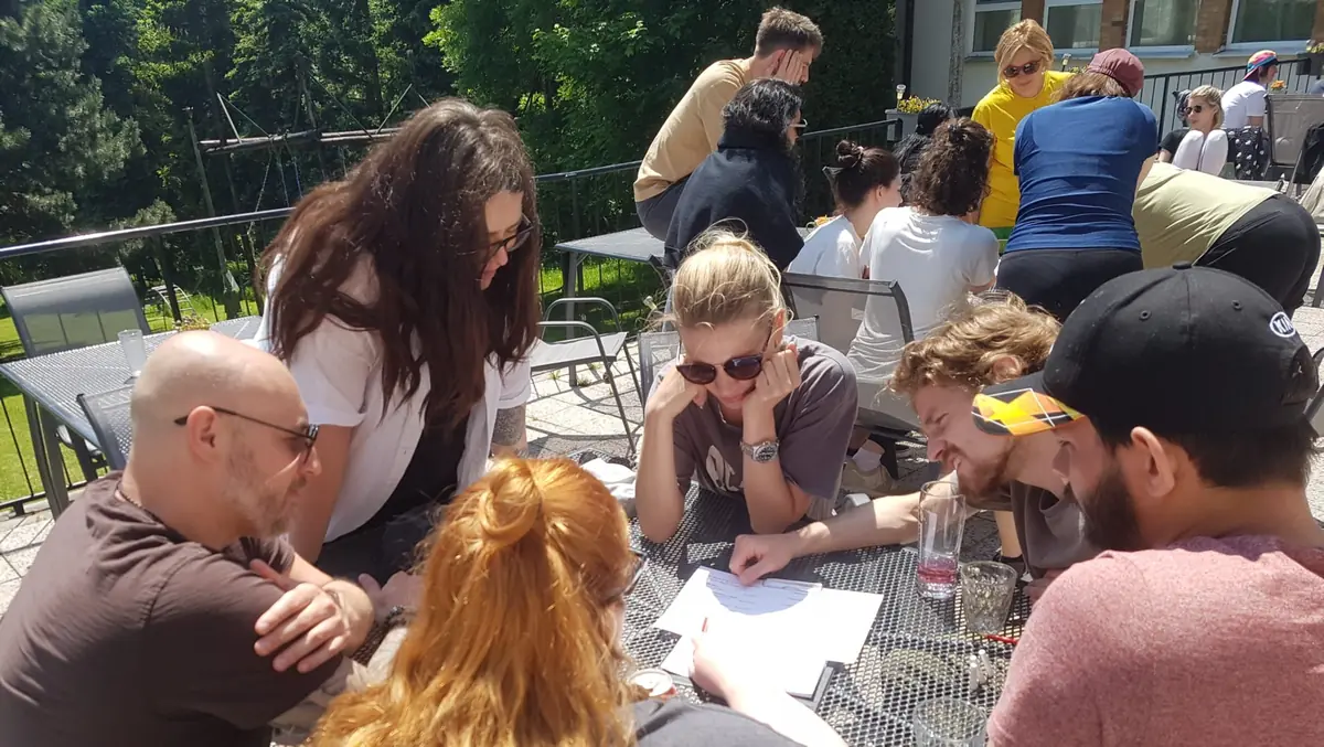 Tímová spolupráca pri outdoor firemnej párty hre na terase počas slnečného dňa.