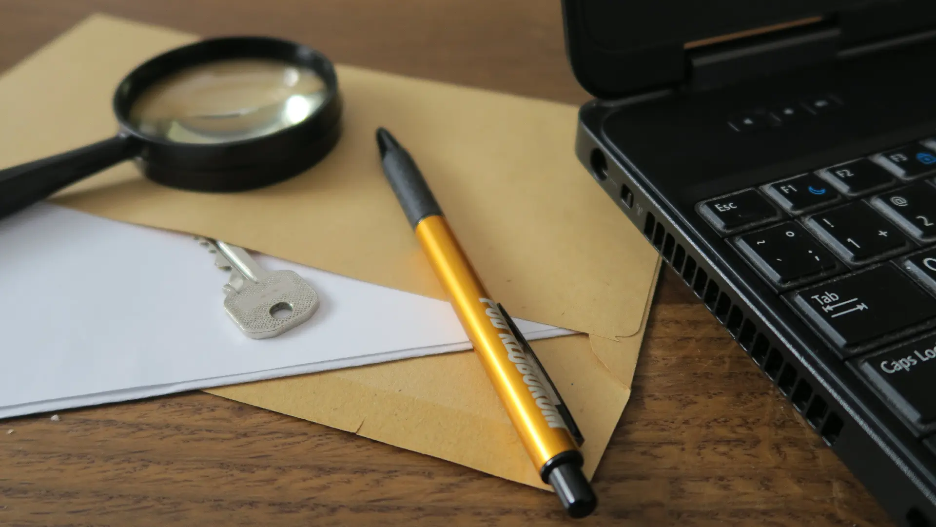 Obálka s kľúčom, lupa, pero a notebook na stole, titulný obrázok šifrovacej hry Príbeh sa začína.