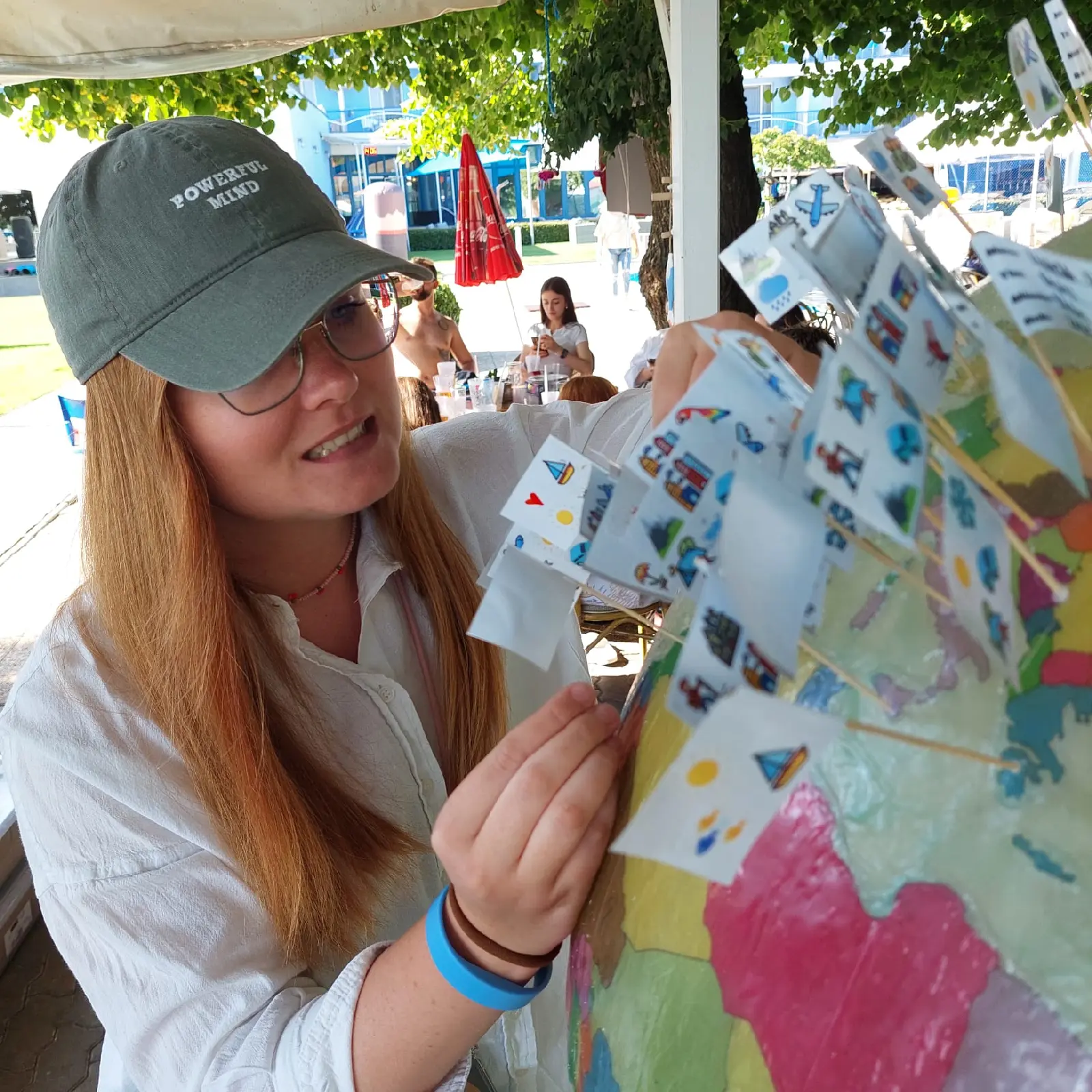 Účastníčka teambuildingu vkladá svoj cestovateľský zážitok na spoločný obrí glóbus - tím si tvorí vlastné umelecké dielo