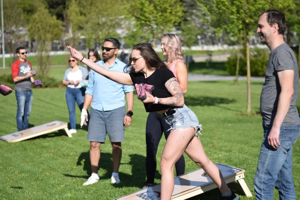 Účastníčka teambuildingu hádže vrecúško do diery v doske pri hre cornhole