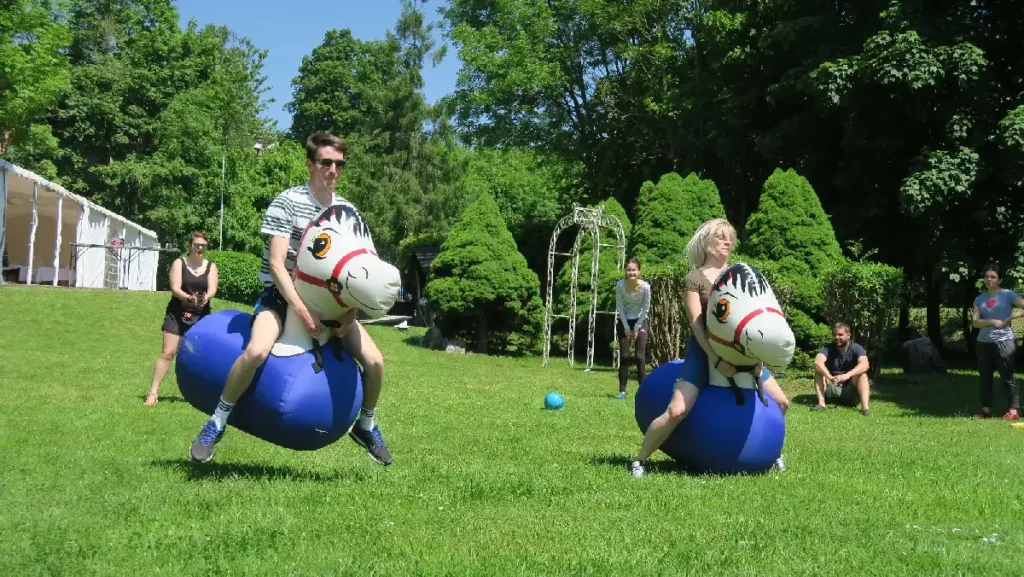 Účastníci sa na teambuildingu zabávajú počas štafety na nafukovacích koníkoch – zábavná pohybová aktivita pre všetky vekové kategórie