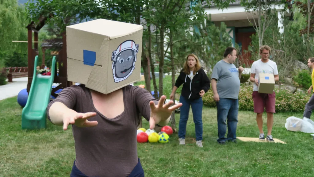 Účastník so zakrytým zrakom zbiera loptičky podľa navigácie tímu – teambuildingová aktivita na komunikáciu a dôveru