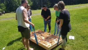 Tím koordinuje pohyb loptičky v labyrinte počas teambuildingovej šifrovacej hry v prírode