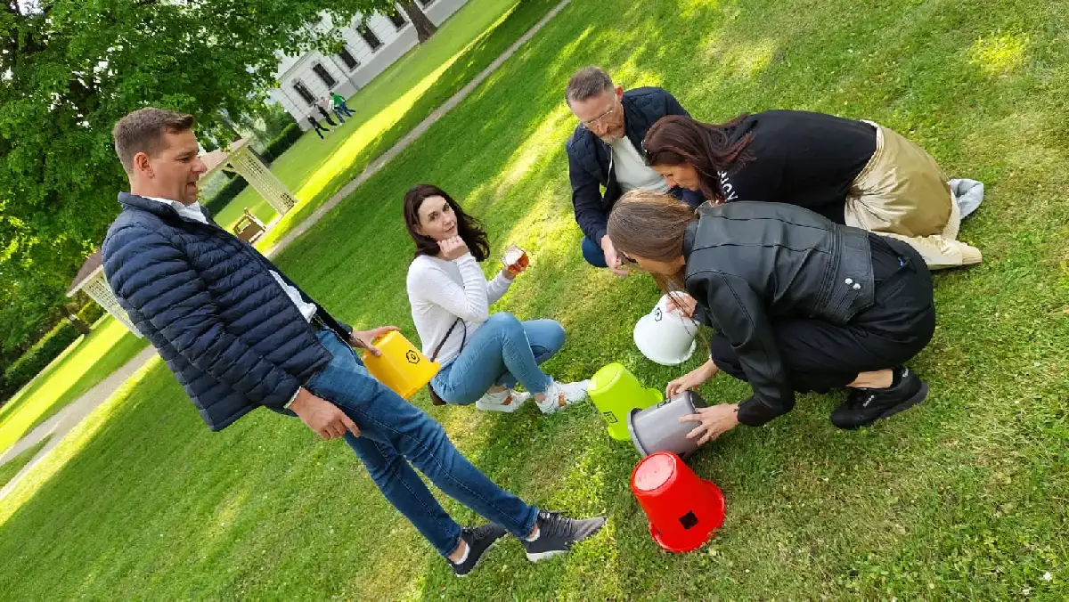 Tím rieši kreatívnu úlohu s vedrami počas teambuildingovej aktivity vonku